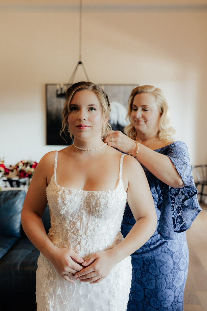 mother of the bride putting on her necklace